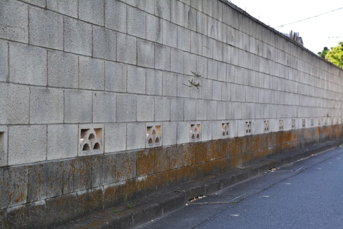 道路沿いに続く老朽化したコンクリートブロック塀。地震時の倒壊リスクが社会課題となっている